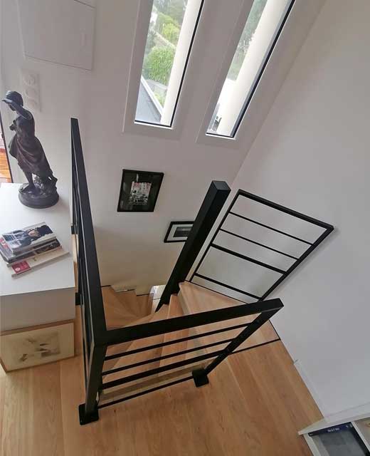 Un escalier hélicoïdal en métal et aux marches en bois