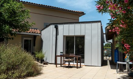 Extension contemporaine de maison avec bardage en zinc réalisée par Cybel Extension, offrant une architecture moderne aux lignes épurées tout en agrandissant l'espace de vie existant.