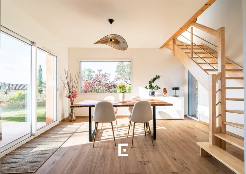 Optimisation de la lumière naturelle au rez-de-chaussée. Se trouve une salle à manger avec un escalier ajouré pour laisser passer la lumière.