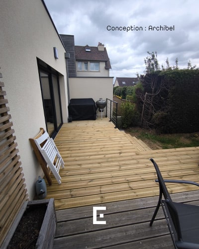 Vue de côté d'une terrasse en bois intégrée à l'aménagement extérieur de la maison.