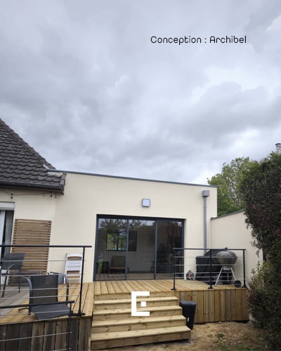 Extension de maison moderne avec grandes baies vitrées donnant sur une terrasse.